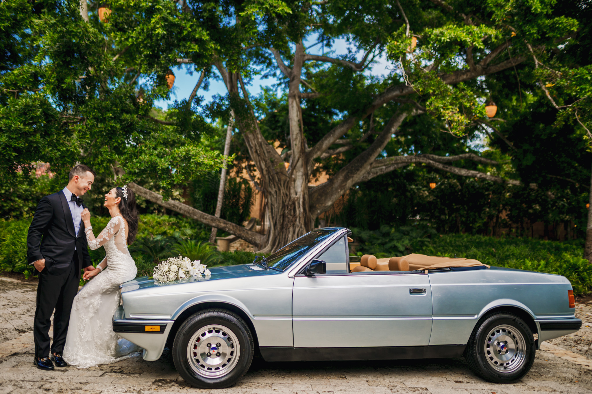 A luxury wedding at Dorado Beach Ritz Carlton Reserve, with a bride and groom standing next to a silver car on the beach.